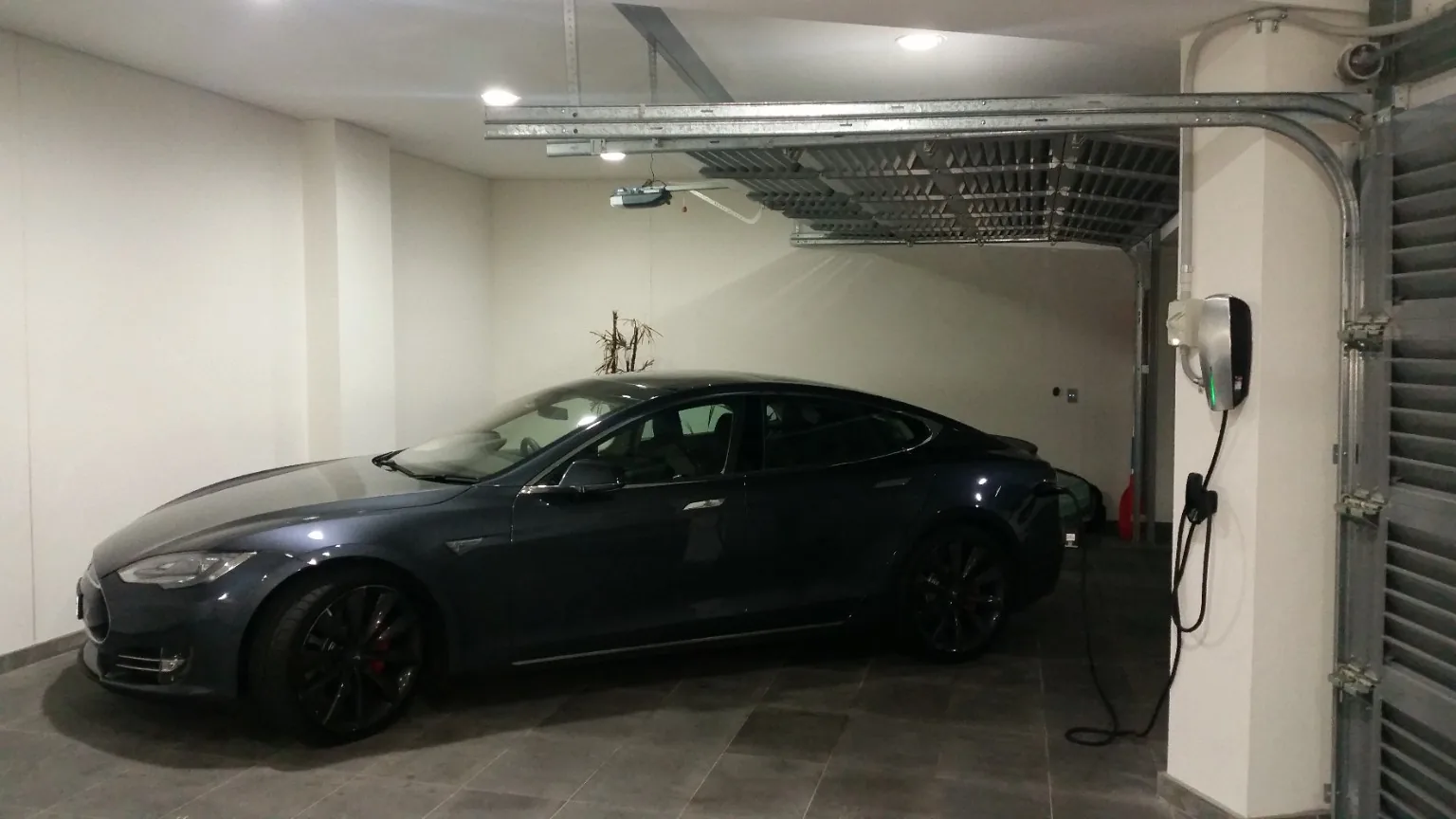 Tesla parked in a garage with a wall-mounted EV charger